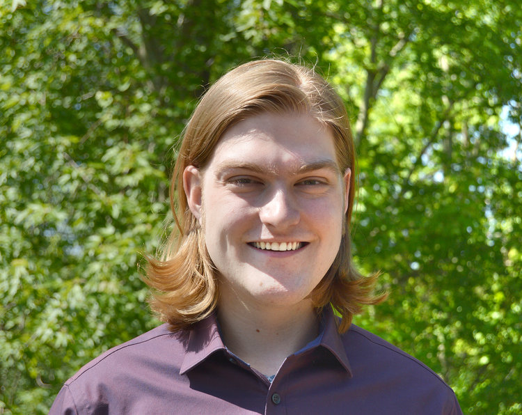 Luke Isenga on a green backdrop smiling