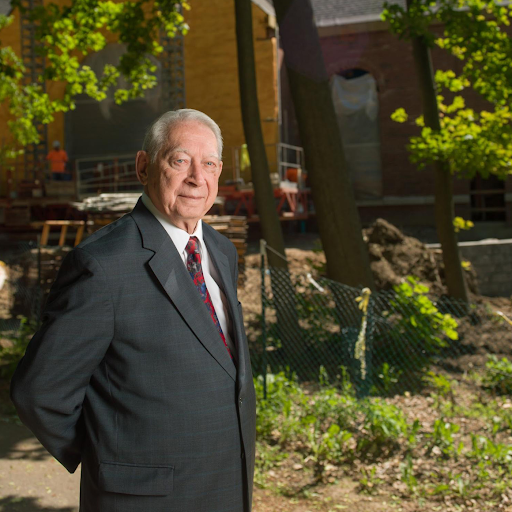 Ted Thompson wearing a suit, standing in front of a construction project