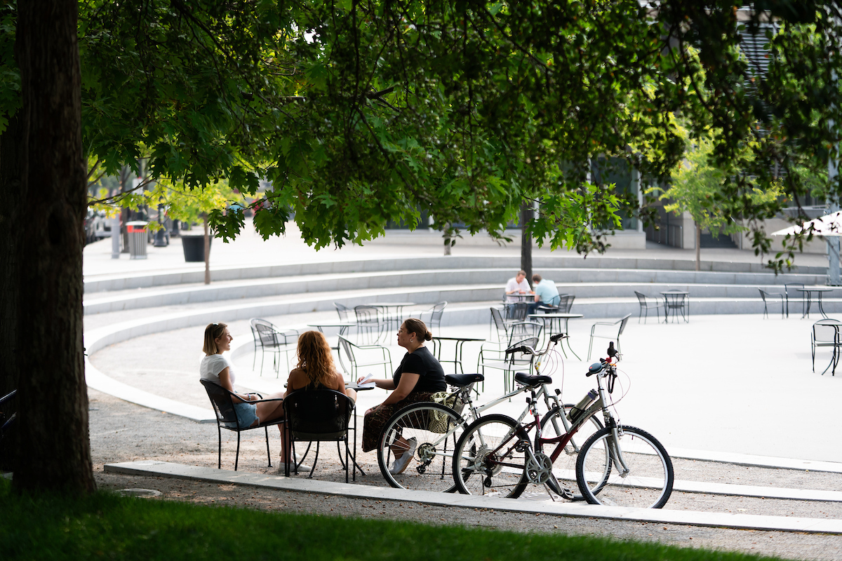 Dr. Lendrum, Arabella Cummings and Aquinas' writer sit at a table in Rosa Parks Circle