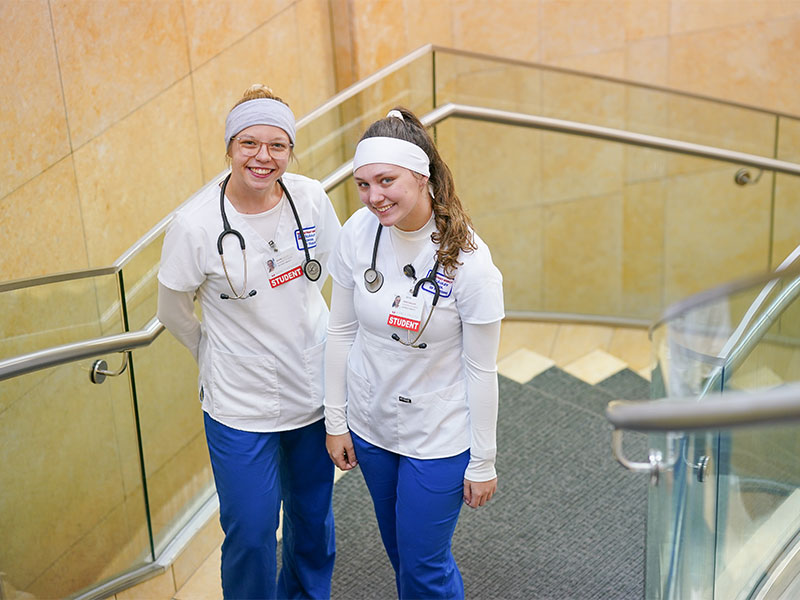 Two nursing students in scrubs smiling