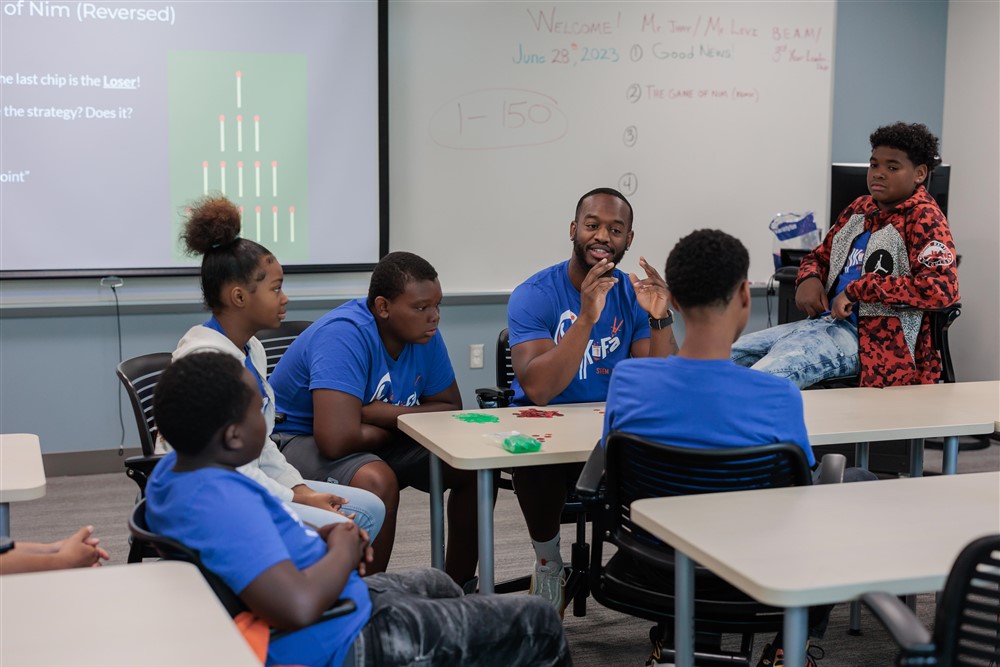 Students and teacher speaking around a table in a classroom